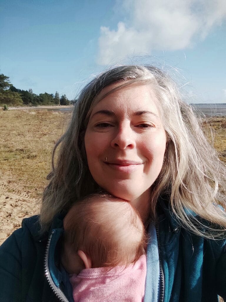 Johanna Sandretto avec son bébé en portage. En plein air et souriante.