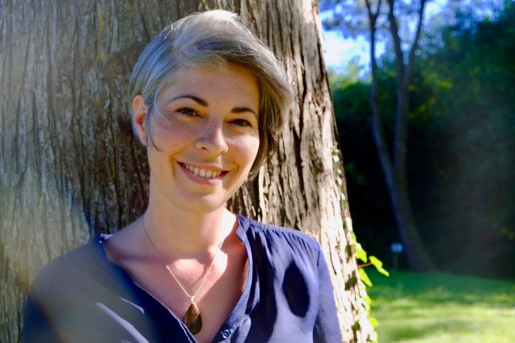 Photo portrait de Johanna Sandretto contre un arbre en pleine nature. Souriante