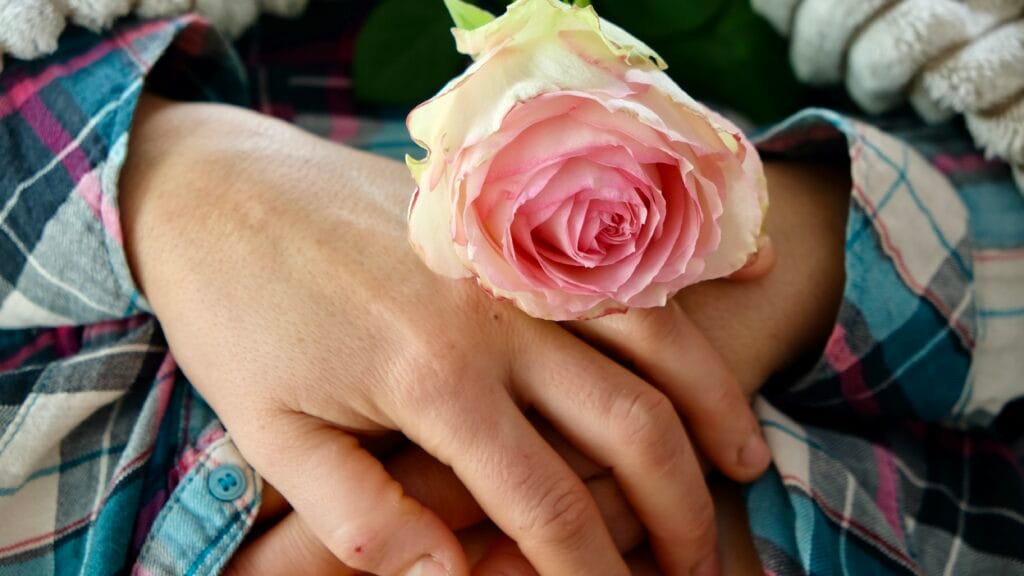 Mains posées sur le coeur avec une rose. Pendant une séance de soin d'onction